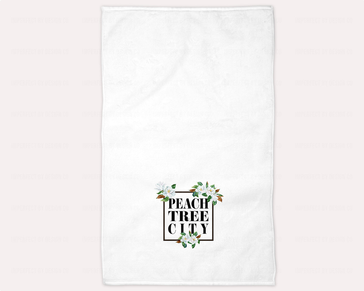 A beautiful and absorbent hand towel featuring a black frame and delicate Magnolia Blossoms, with the words "Peachtree City" in bold letter design. Ideal for guest baths and perfect for bed and breakfast and vacation rental owners | imperfect by design co
