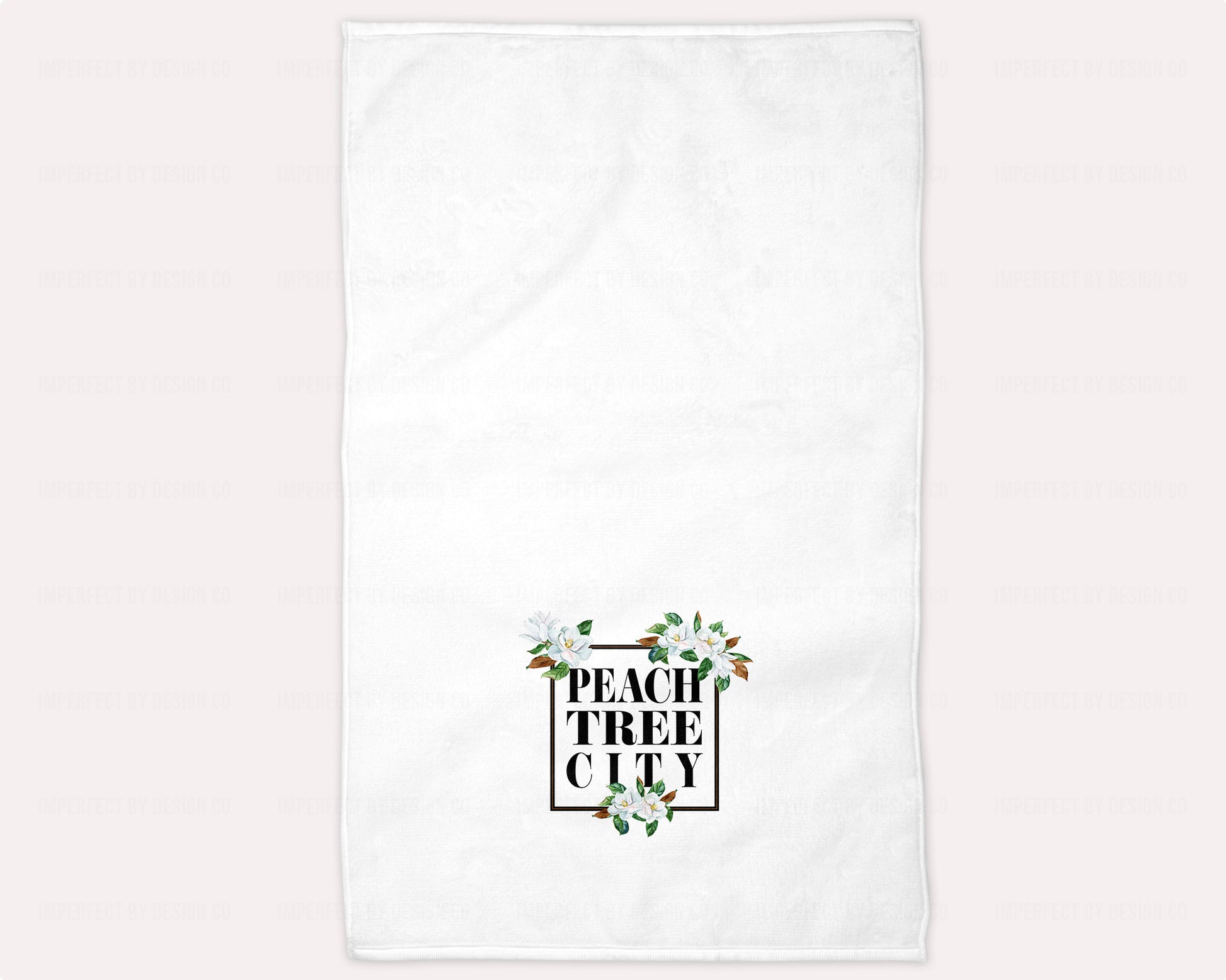 A beautiful and absorbent hand towel featuring a black frame and delicate Magnolia Blossoms, with the words "Peachtree City" in bold letter design. Ideal for guest baths and perfect for bed and breakfast and vacation rental owners | imperfect by design co