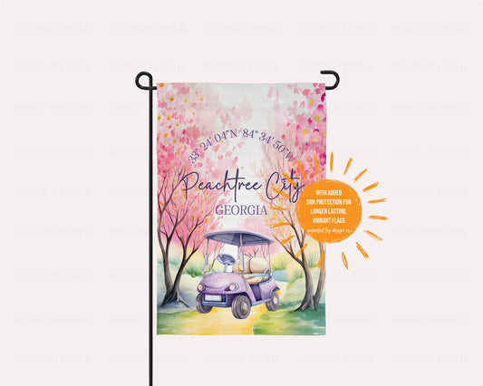 Garden flag with Peachtree City, Georgia design featuring a golf cart and cherry blossoms. Sun shaped blurb reads 'with added sun protection for longer lasting vibrant flags' 'imperfect by design co'. Exclusive design.