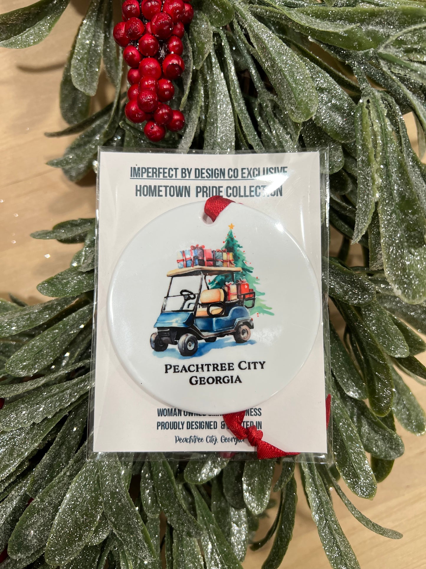 display of Glossy white double-sided ornament with festive blue golf cart and red ribbon, featuring custom city or family name.