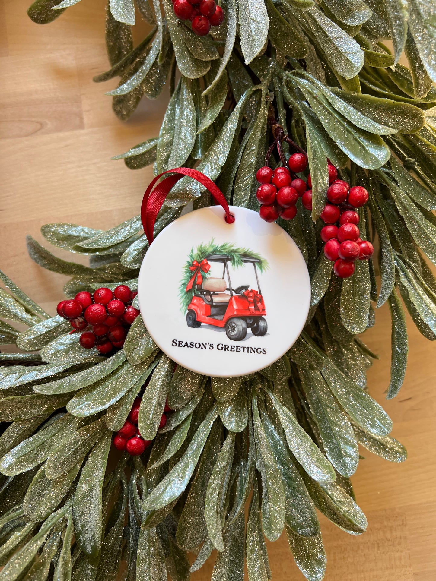 White disk Christmas ornament featuring a festively decorated red golf cart with "Season's Greetings"