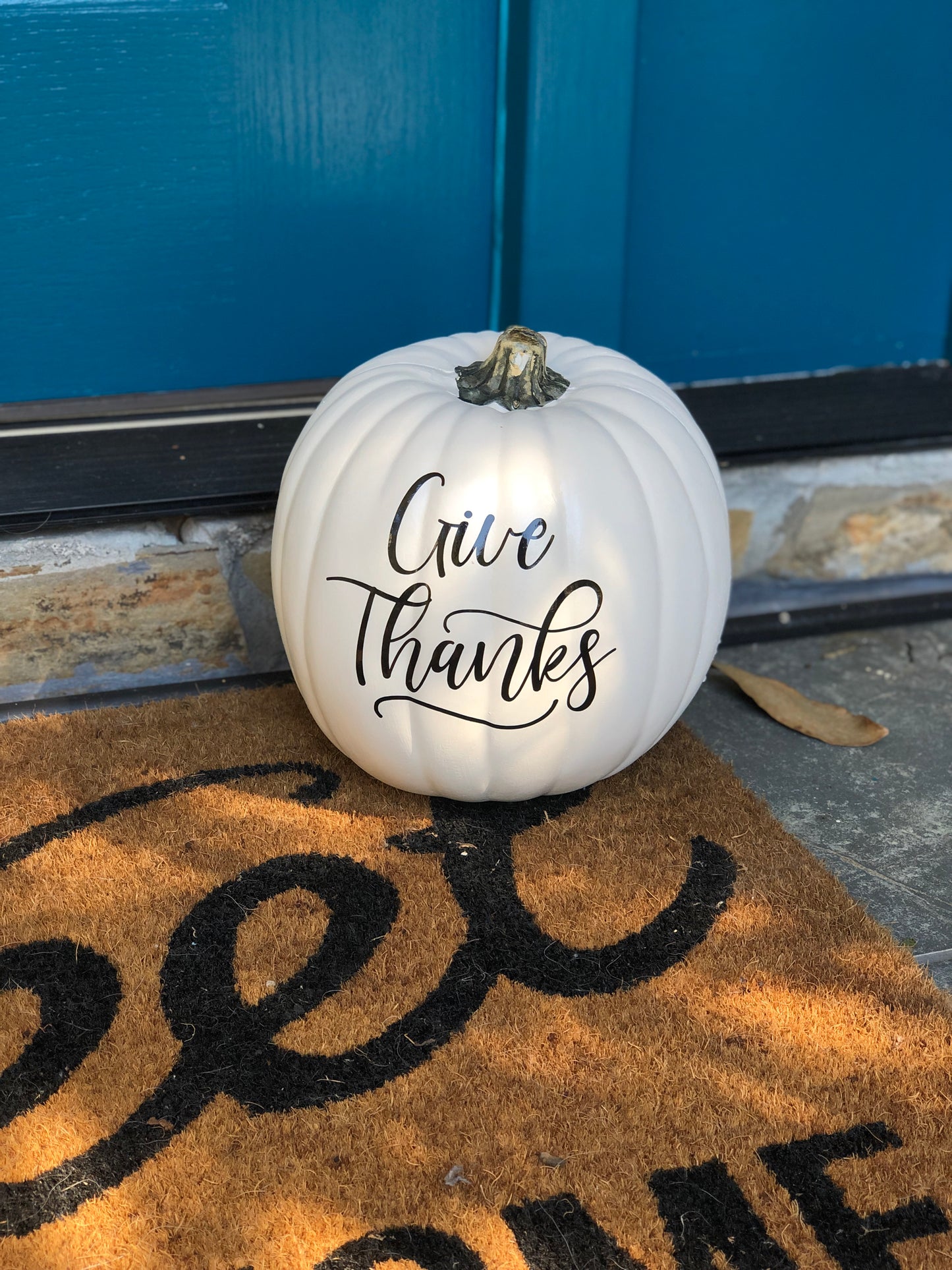 Medium white decorative pumpkin with "give thanks" text on door step
