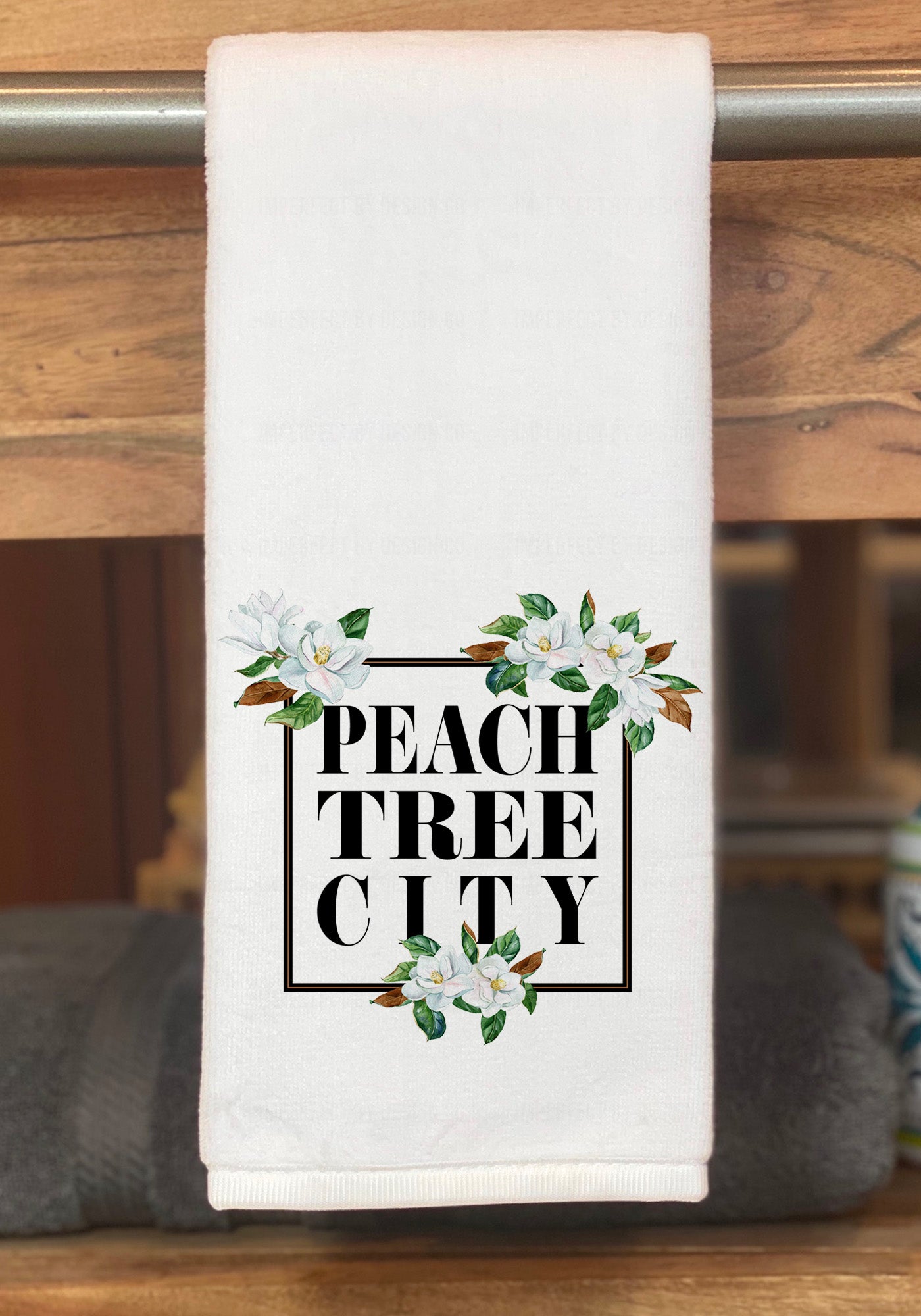 Elevate your guests' bathroom experience with this personalized hand towel, featuring a stunning Magnolia Blossom design and "Peachtree City" lettering in black | imperfect by design co