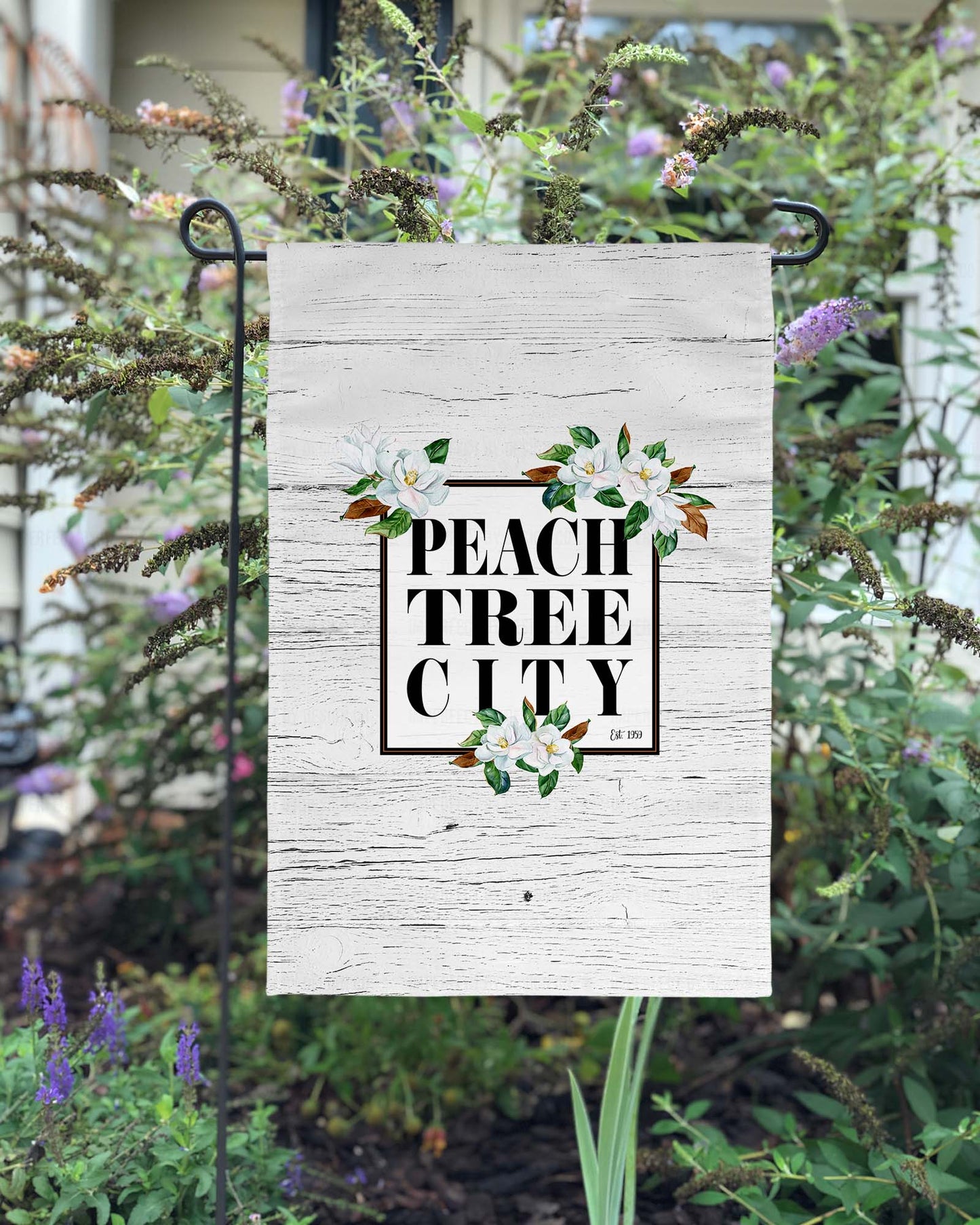 Magnolia, Peachtree City - Garden Flag showcasing an elegant black frame with stunning magnolia blooms on a crisp white faux wood background. Durable, weather-resistant material ensures long-lasting use. Must-have for any proud Peachtree City resident or admirer of its beauty | imperfect by design co
