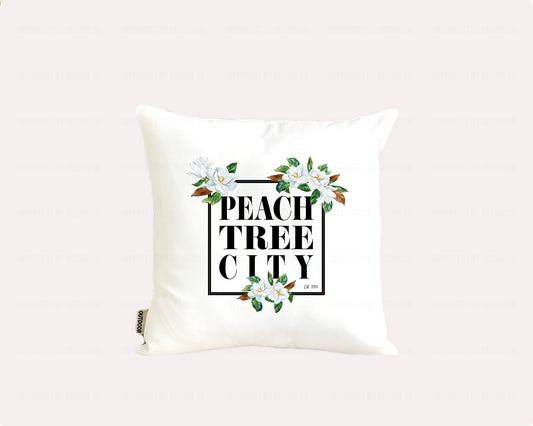 16x16 inches An elegant white outdoor pillow with a weather-resistant poly coating, featuring a stunning magnolia bloom design and the words "Peachtree City est. 1959" inside a black frame | imperfect by design co imperfect by design co