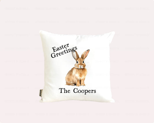 White personalized indoor outdoor pillow  adverting pillow cover with Easter bunny design and text reading "The Coopers" on a pale pink background.