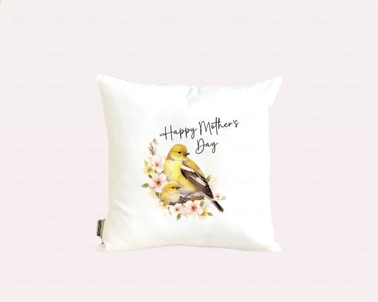 White decorative pillow advertising pillow cover with a female Goldfinch and it's nestling sitting on a branch with pink flowers. Text on pillow reads "Happy Mother's Day' . Placed on a pale pink background  | imperfect by design co
