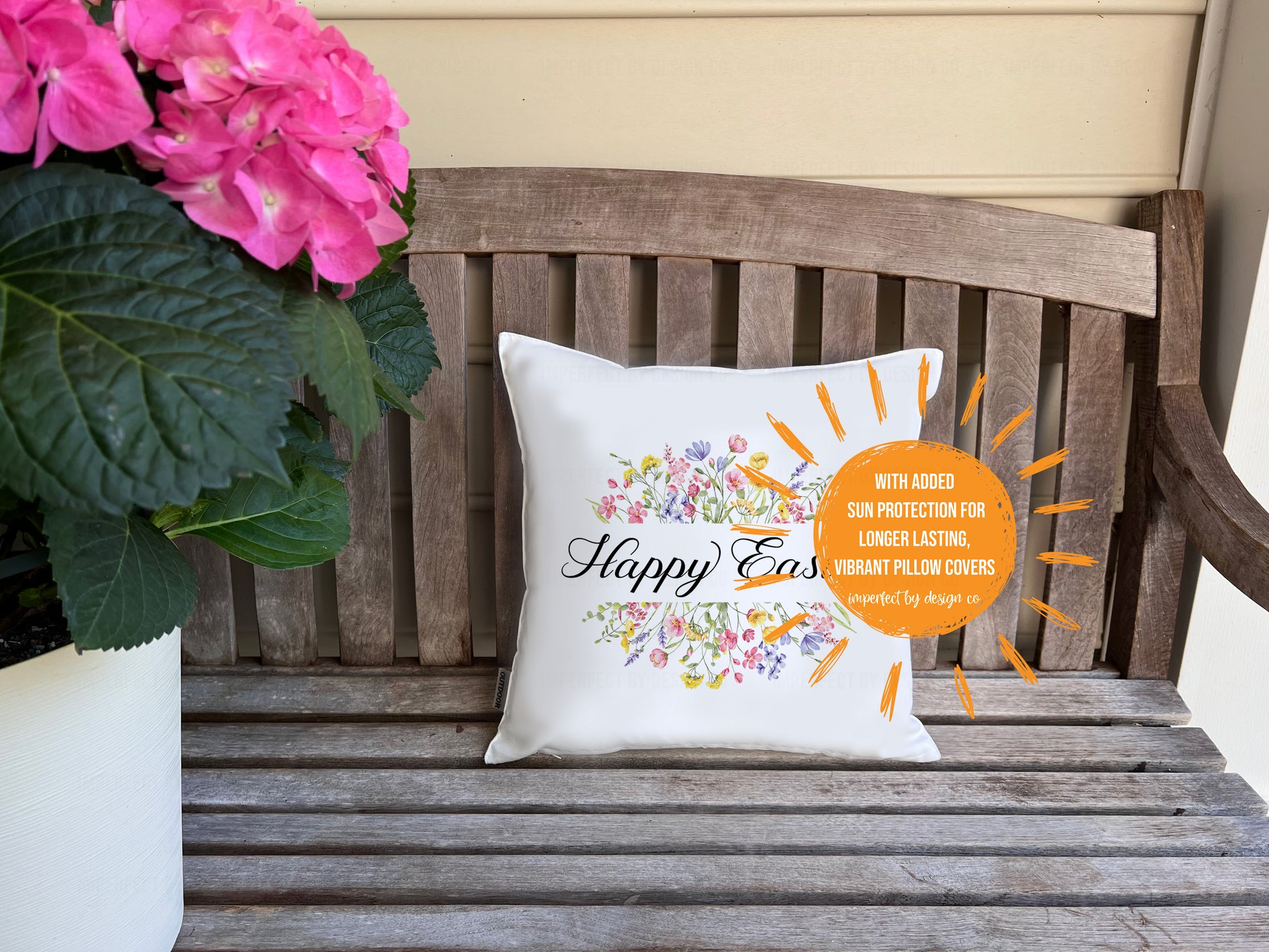 White decorative indoor outdoor pillow advertising pillow cover on porch bench flanked by pink hydrangea. Pillow features flowers and text on pillow cover reads 'Happy Easter'.  | imperfect by design co