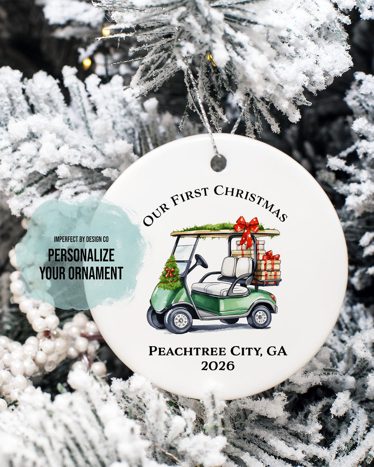 imperfect by design co exclusive
A round white personalized Christmas ornament hanging on a frosted Christmas tree. The ornament features a printed green golf cart carrying a gift box and the text 'Our First Christmas' and 'Peachtree City, GA 2026,' plus a light blue tag that says 'Personalize Your Ornament.