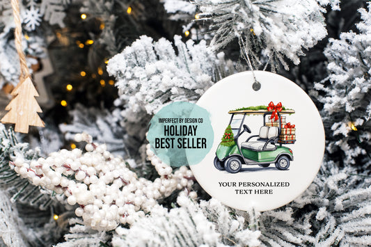 imperfect by design co exclusive design
A round white Christmas ornament hanging on a frosted Christmas tree. The ornament features an illustration of a green golf cart carrying a gift box with a red bow, plus printed text reading 'IMPERFECT BY DESIGN CO HOLIDAY BEST SELLER' and 'YOUR PERSONALIZED TEXT HERE'.