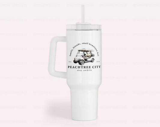 A white 40oz insulated stainless steel tumbler featuring a white golf cart and text on the front and back. Text reads 'family, friends, small hometown feel' 'Est. 1959' Peachtree City stay awhile'  | imperfect by design co exclusive