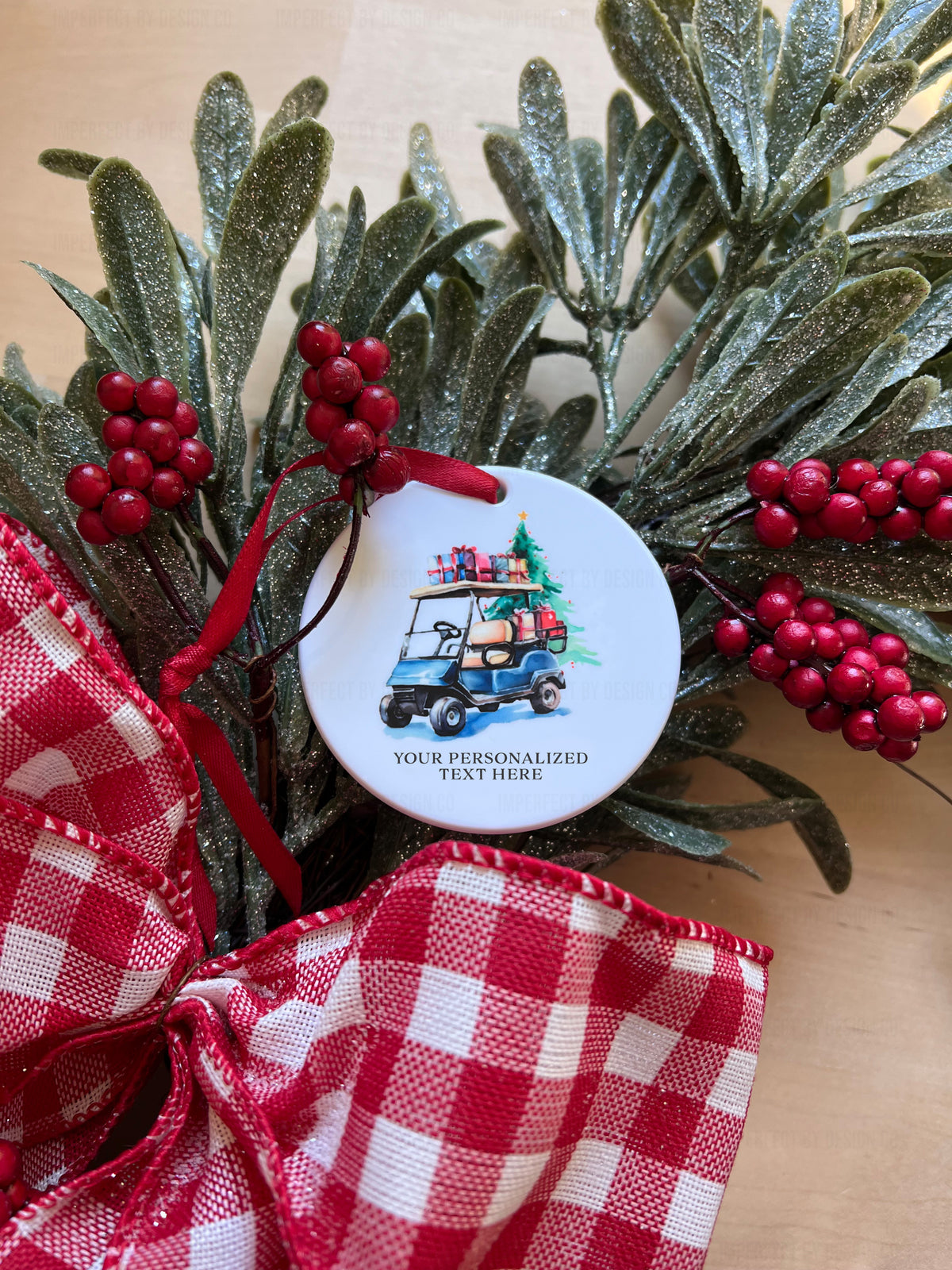 Round white disc Christmas ornament featuring a blue golf cart loaded with presents.