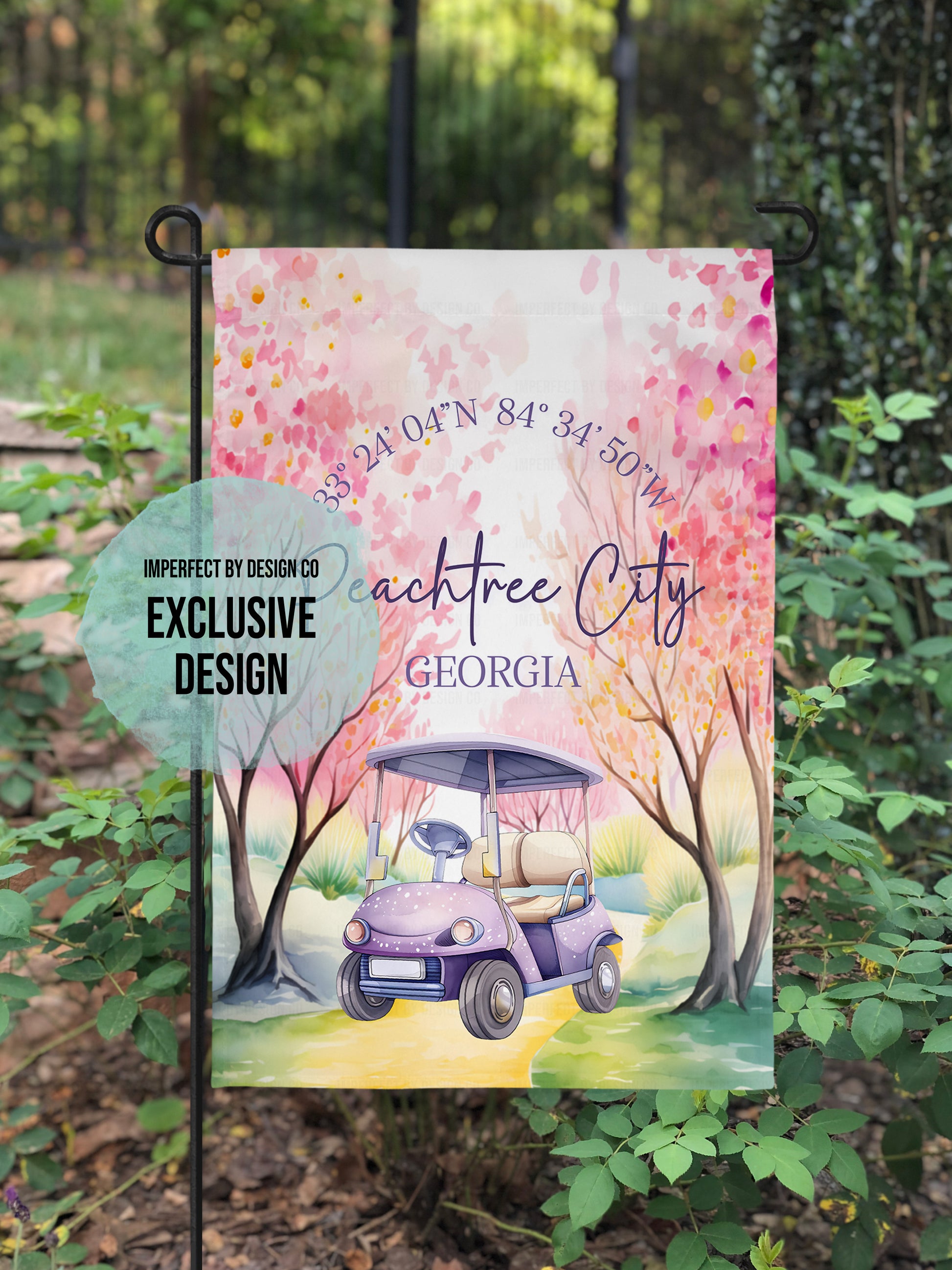 Decorative garden flag with a golf cart design and text, placed outdoors among greenery. Blue text blurb reads 'imperfect by design co exclusive'