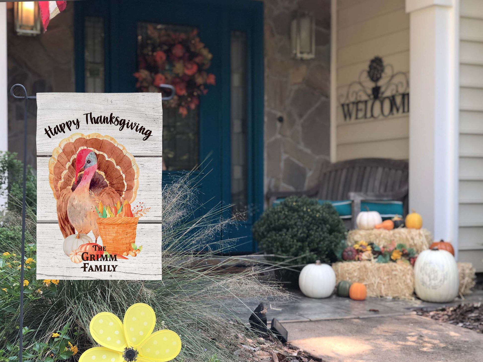 Full view of the personalized Thanksgiving flag featuring family name and festive design on a decorated front porch.