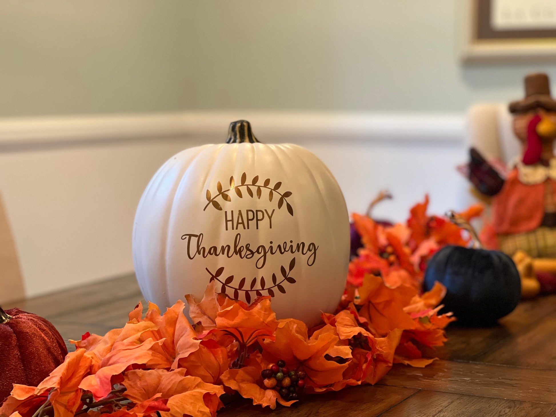 Close-up of Happy Thanksgiving text with laurel design on pumpkin sat on festive table
