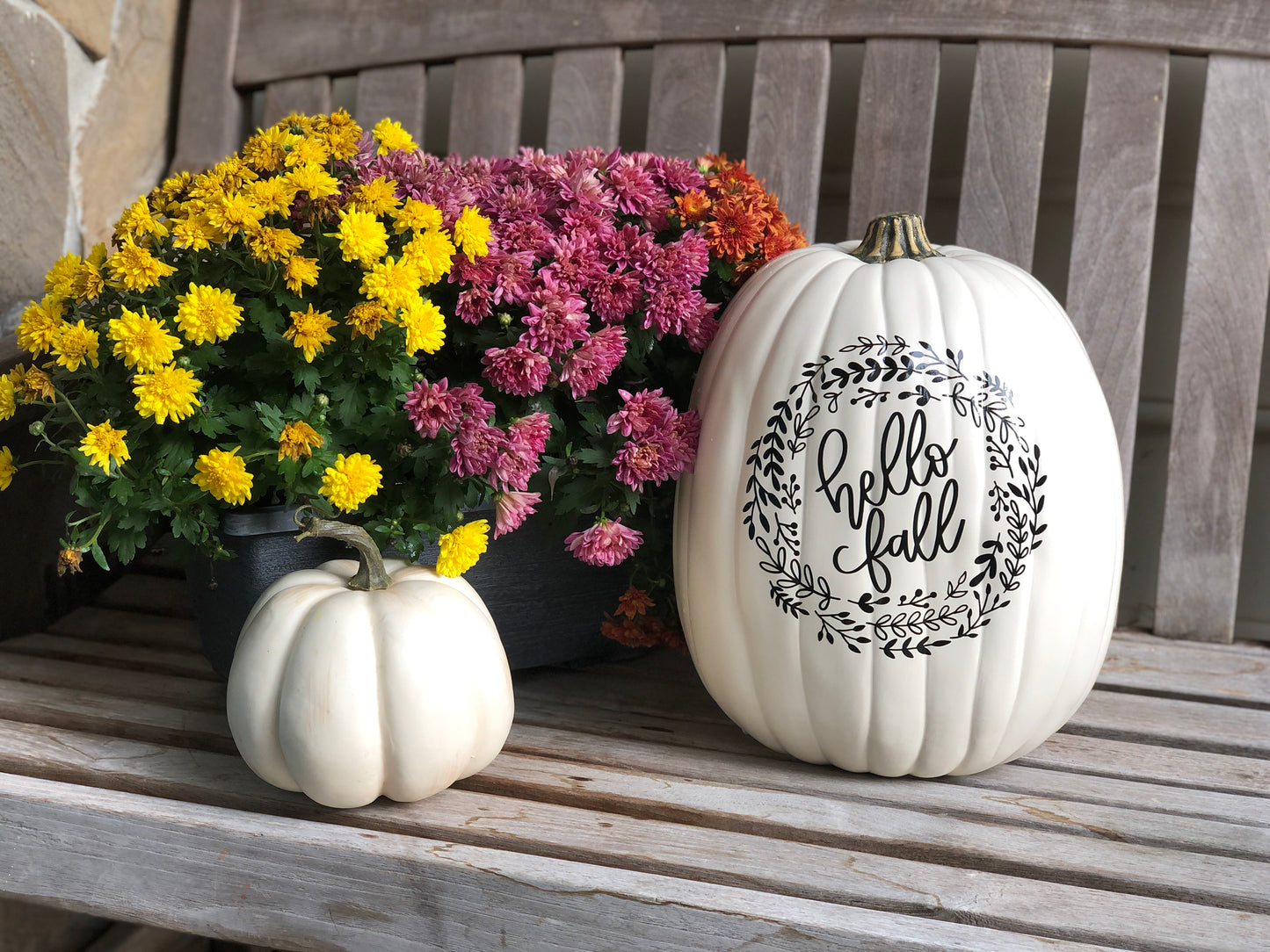 Large decorative faux pumpkin with Hello Fall and black appliqué and colorful mums on display
