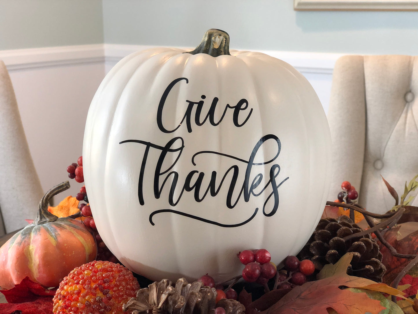 Thanksgiving pumpkin decor with Give Thanks text in black on a festive table setting