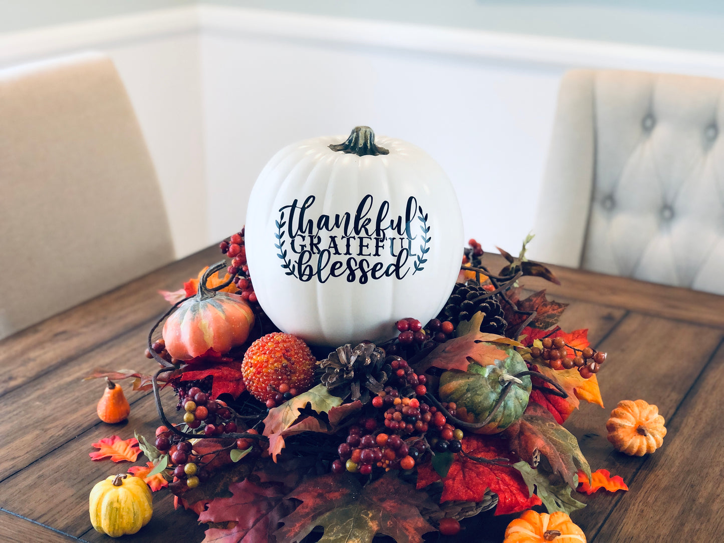 Thanksgiving pumpkin decor with Thankful Grateful Blessed text in black on a festive table setting