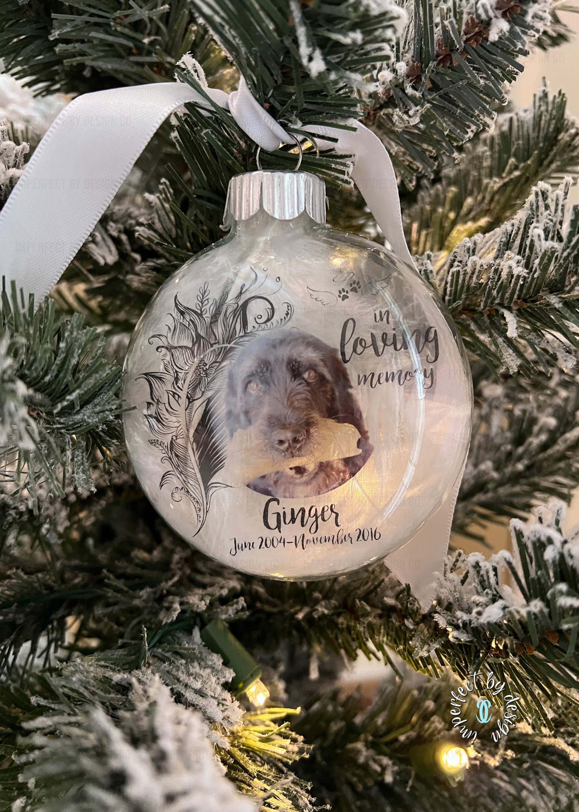 Close-up of custom pet memorial ornament with photo, "In Loving Memory" text, and ribbon for hanging.
