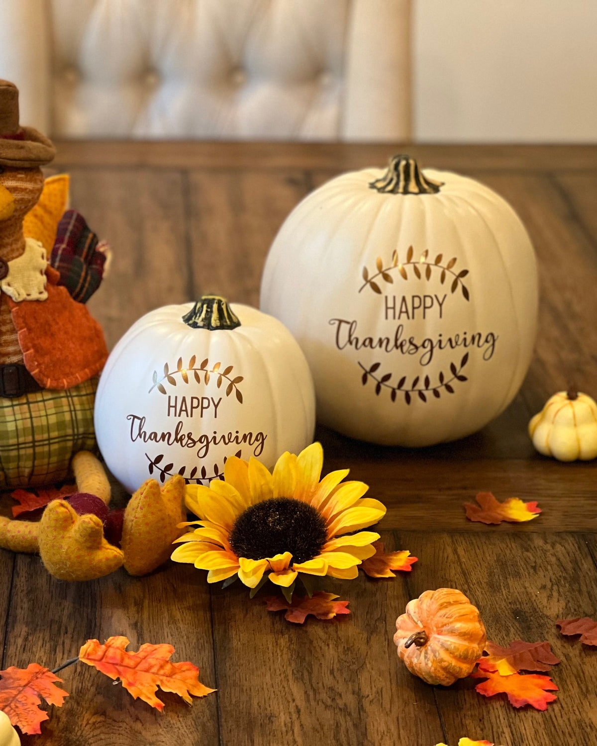 Fall decor pumpkins with Happy Thanksgiving and laurel design sitting on a festively decorated table