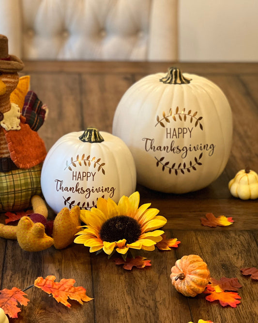 Fall decor pumpkins with Happy Thanksgiving and laurel design sitting on a festively decorated table