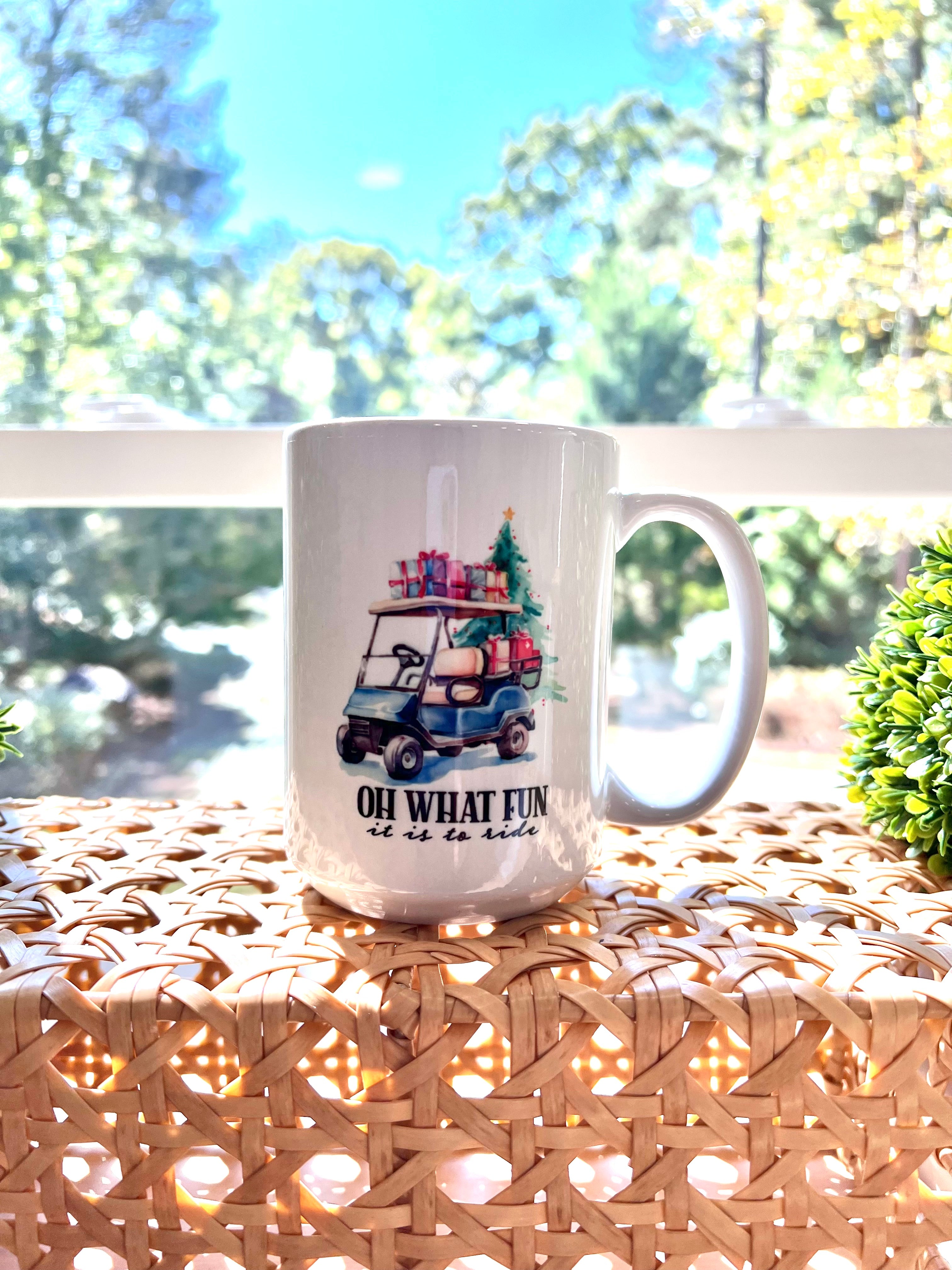 Festive Christmas coffee mug with blue golf cart, Christmas tree, gifts, and holiday design. Text reads "Oh What Fun it is to ride"
