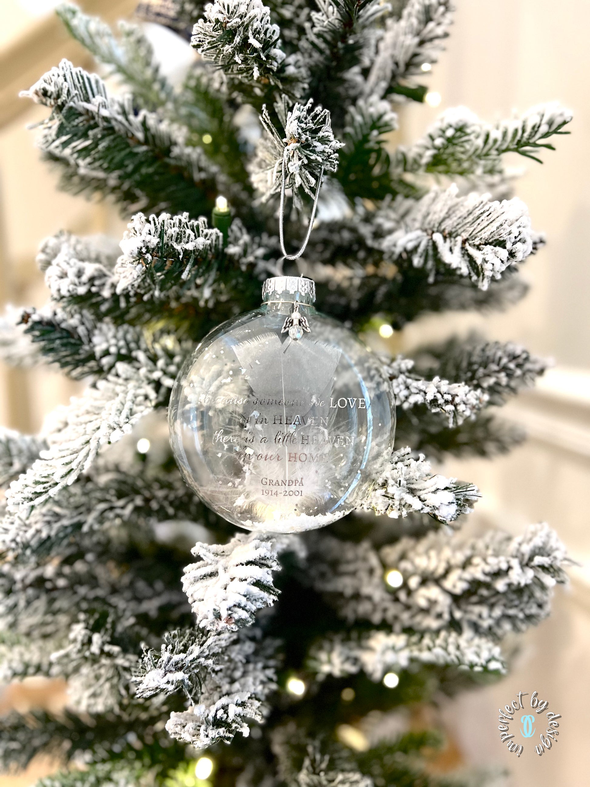 Memorial Ornament Hanging on Christmas Tree – The personalized memorial ornament hanging on a tree, with its silver metallic braided cord, surrounded by warm holiday lights, creating a sentimental tribute.