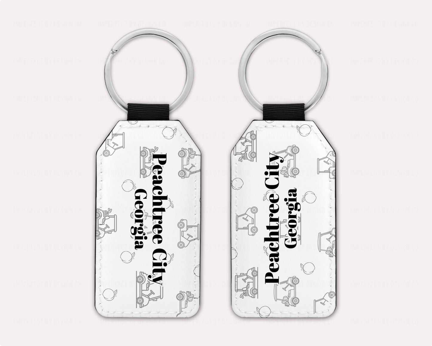 Exclusive design on 2 white faux leather keychain, with a golf cart and peach pattern text reads 'Peachtree City' with 'Georgia' placed right beneath.  View of both sides on a pale pink background | imperfect by design co 