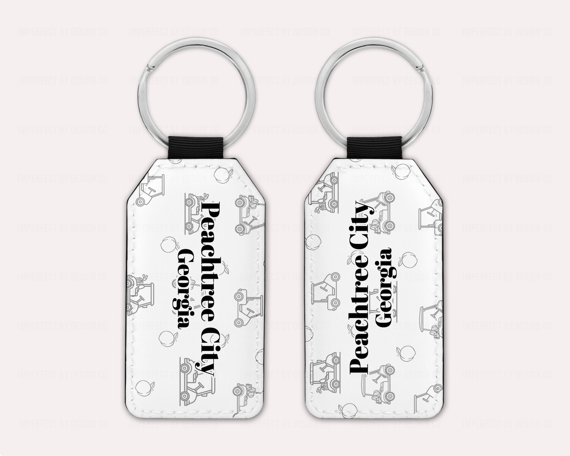 Exclusive design on 2 white faux leather keychain, with a golf cart and peach pattern text reads 'Peachtree City' with 'Georgia' placed right beneath.  View of both sides on a pale pink background | imperfect by design co 