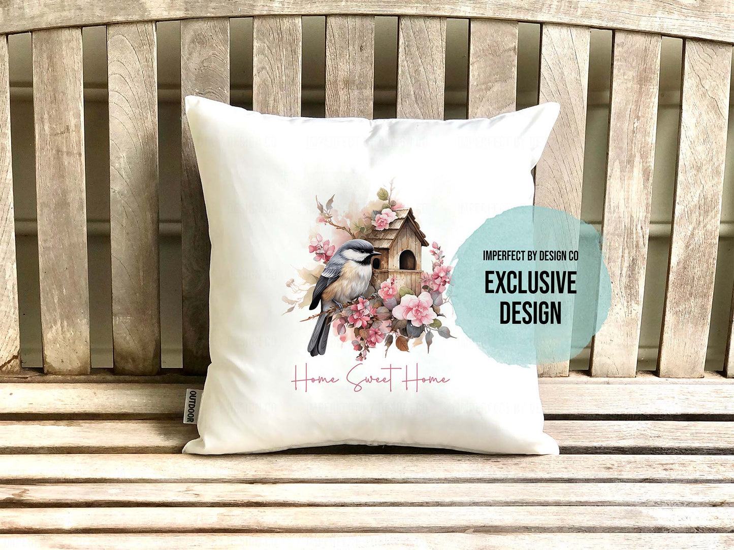 Decorative pillow with Chickadee and flower design on a wooden bench. Text blurb reads 'imperfect by design co exclusive' 