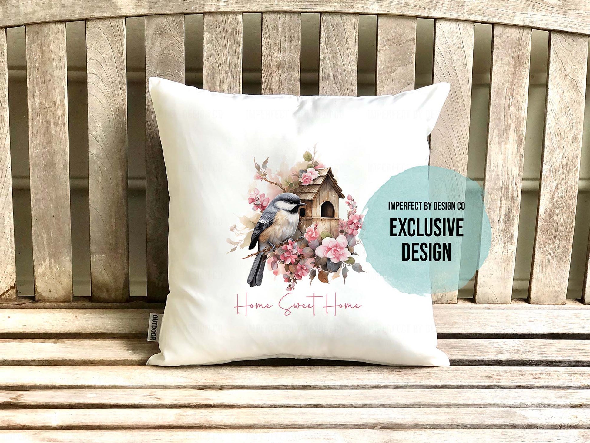 Decorative pillow with Chickadee and flower design on a wooden bench. Text blurb reads 'imperfect by design co exclusive' 