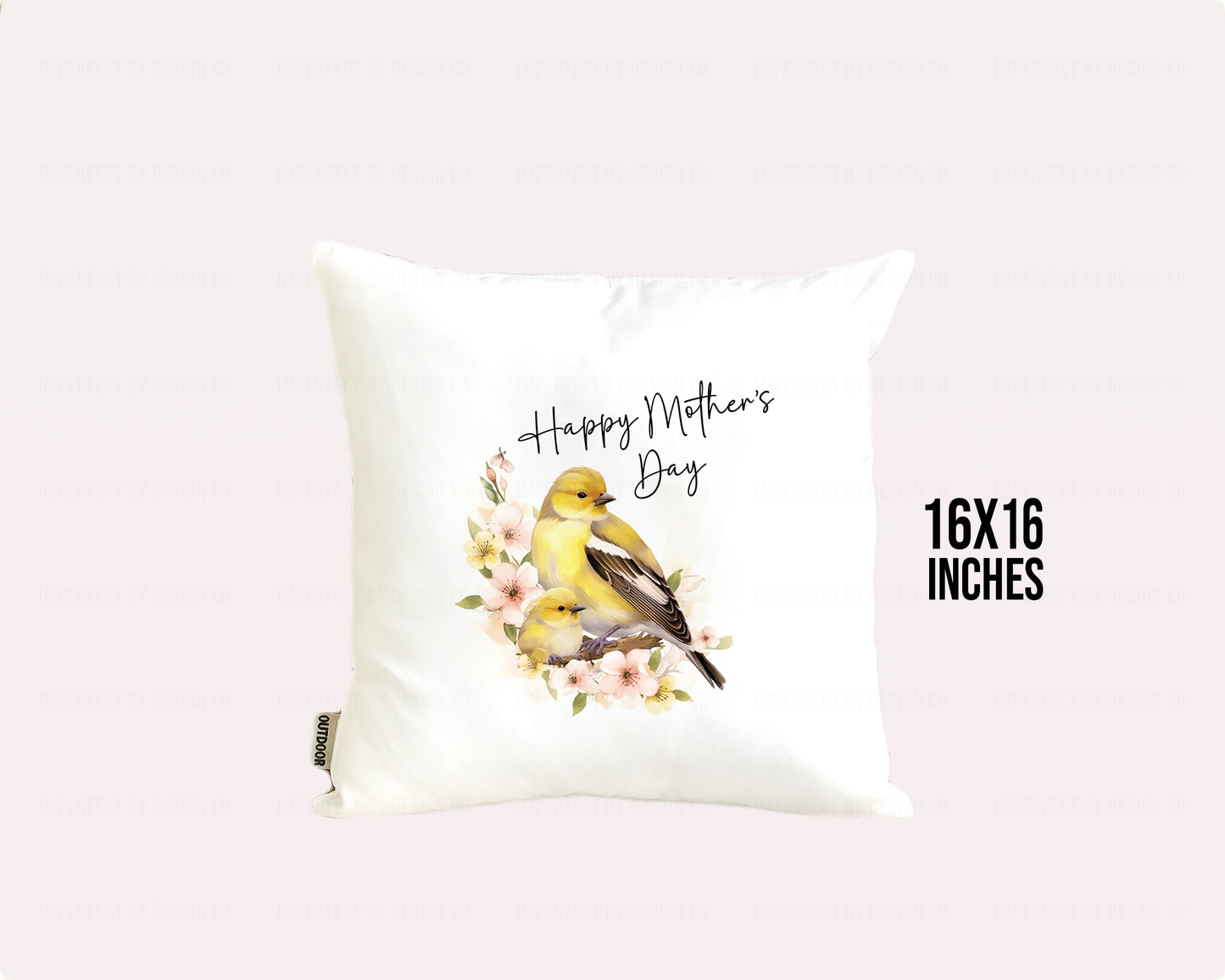 White decorative pillow advertising pillow cover with a female Goldfinch and it's nestling sitting on a branch with pink flowers. Text on pillow reads "Happy Mother's Day' . Placed on a pale pink background. Graphic on background reads 16x16 inches.  | imperfect by design co