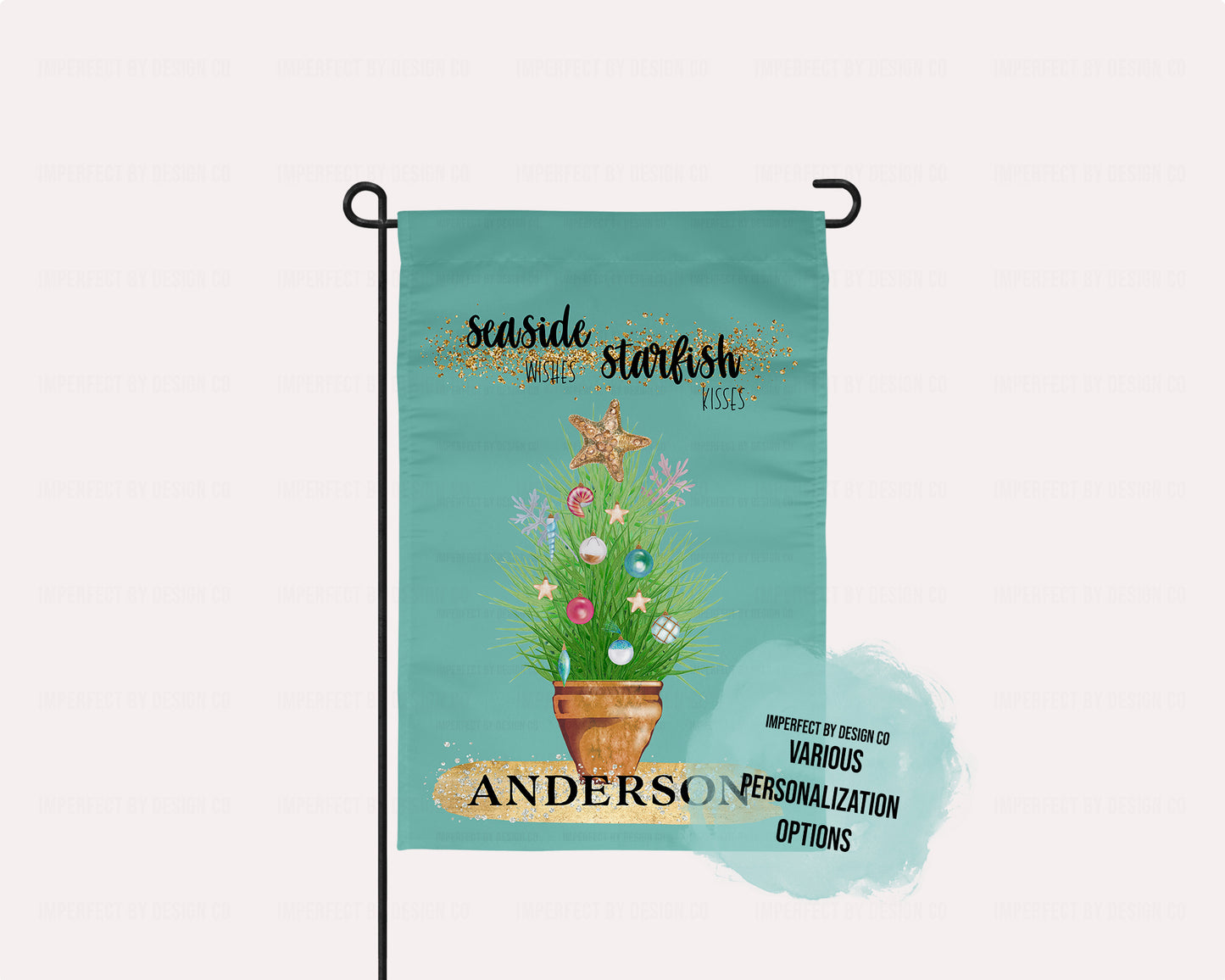 Personalized with a Last Name Flag teal featuring potted ornamental grass adorned with Christmas tree bulb and topped with a golden starfish. The Flag reads 'Seaside Wishes Starfish Kisses'. Below the potted plant there is a large golden brushstroke with black bold text that reads 'Anderson'. The flag is on a flag pole.  A blue blurb that reads ' imperfect by design co' 'Various personalization options'. Place on a garden flag stand on a pale pink background.  An imperfect by design co exclusive design.
