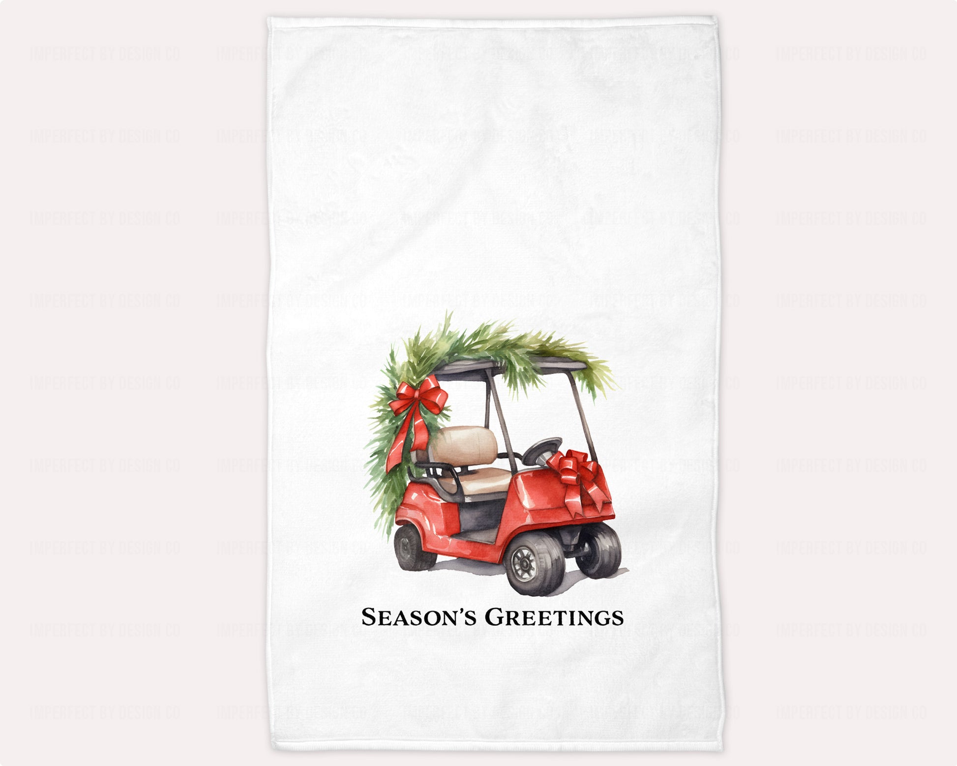 A white towel with a printed design featuring a red golf cart with a green bow on the front, and the text 'Seasons Greetings'.