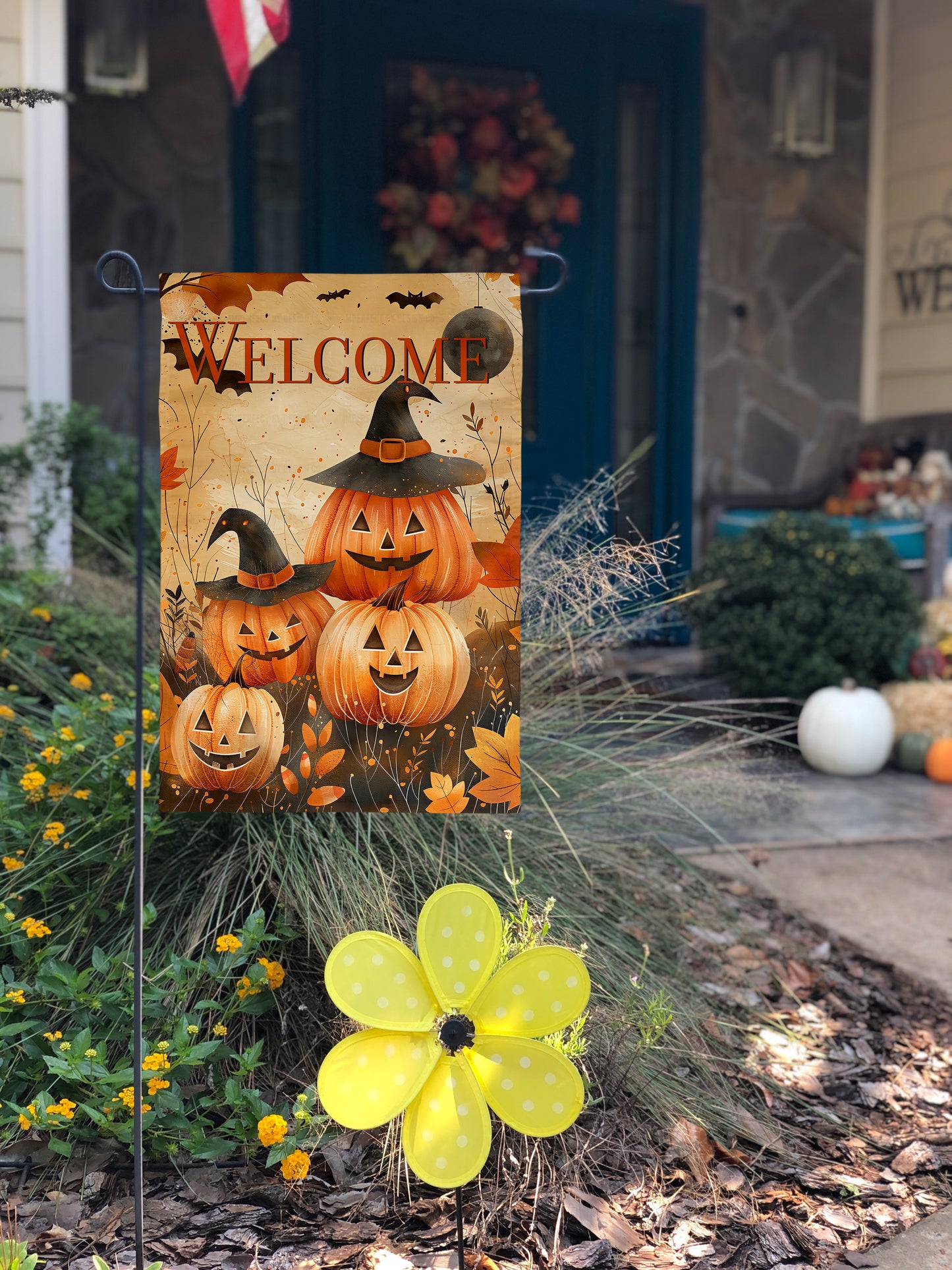 Smiling jack-o-lantern family with witch hats and autumn leaves on the garden flag.
