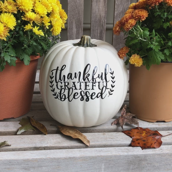 video still of medium white decorative pumpkin text reads thankful, grateful, blessed in black surrounded by mum blossoms