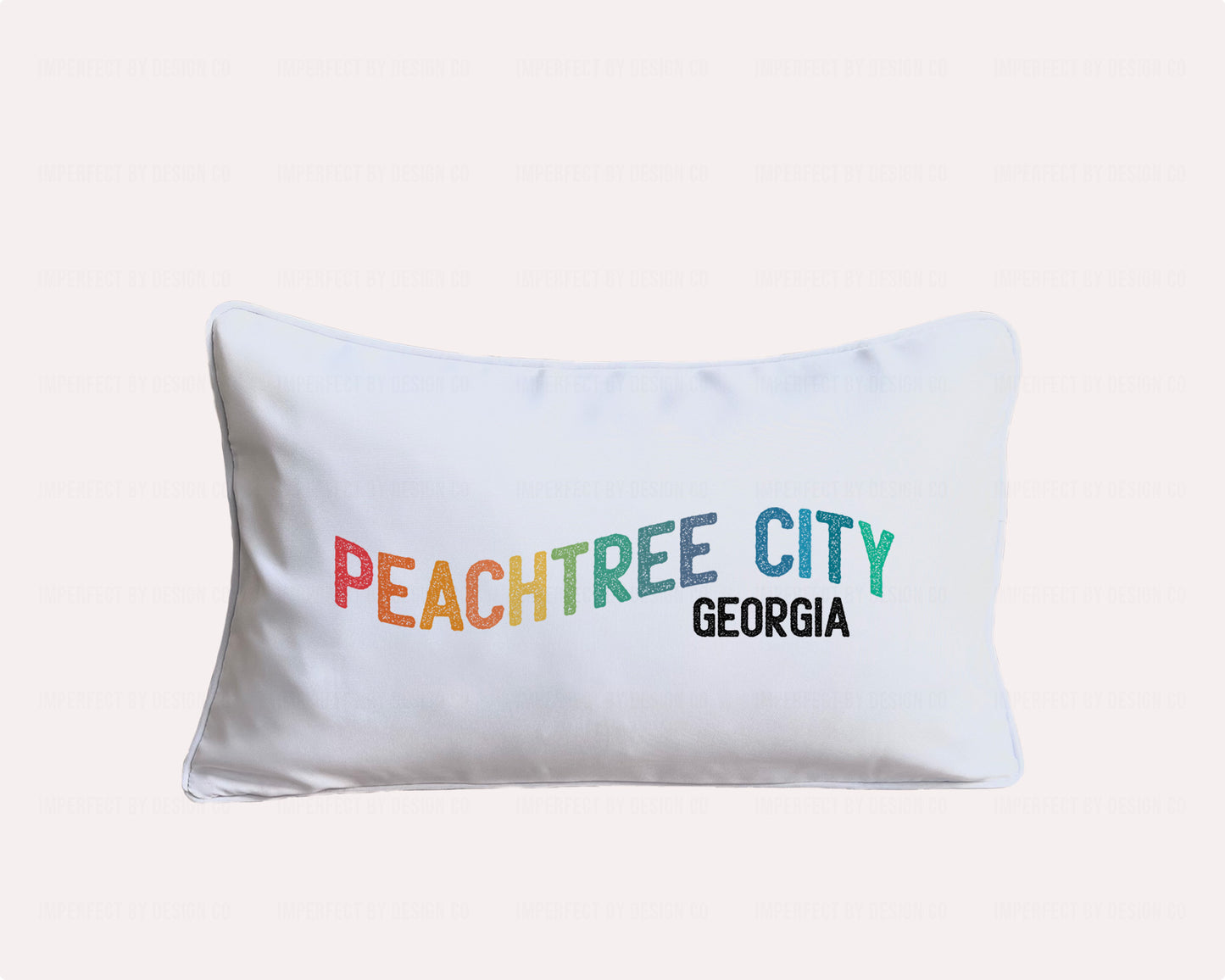 Bring some Southern charm to your outdoor living space with our Peachtree City indoor/outdoor pillow, featuring a vibrant multicolor "Peachtree City, Georgia" design in a playful waving font. The 12x20 inch size is perfect for adding a pop of color to your porch, patio, or pool deck. | imperfect by design co