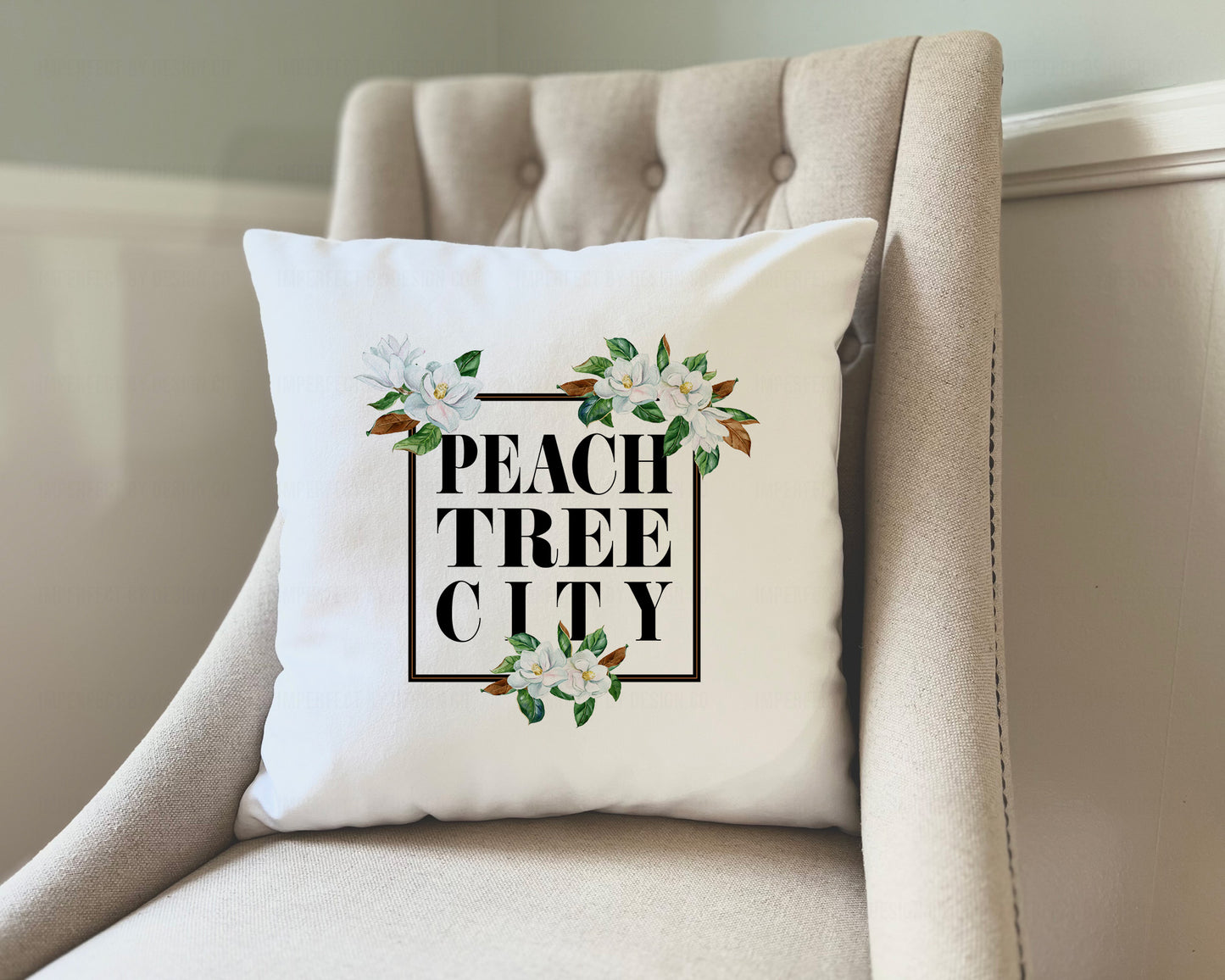 18x18 inches An elegant white velvet pillow cover measuring 18"x18", with a stunning magnolia bloom design and the words "Peachtree City" inside a black frame | imperfect by design co