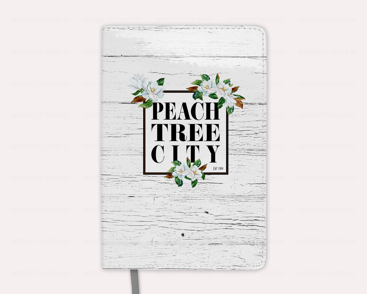 Elevate your desk decor with our Peachtree City magnolia notebook, featuring stunning magnolia blooms on a crisp white faux wood background, and Peachtree City name and date established. Perfect for organizing your notes and thoughts in style. | imperfect by design co